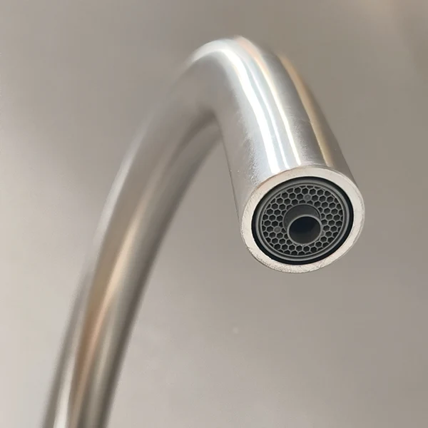 Close view of a faucet spout and outlet.