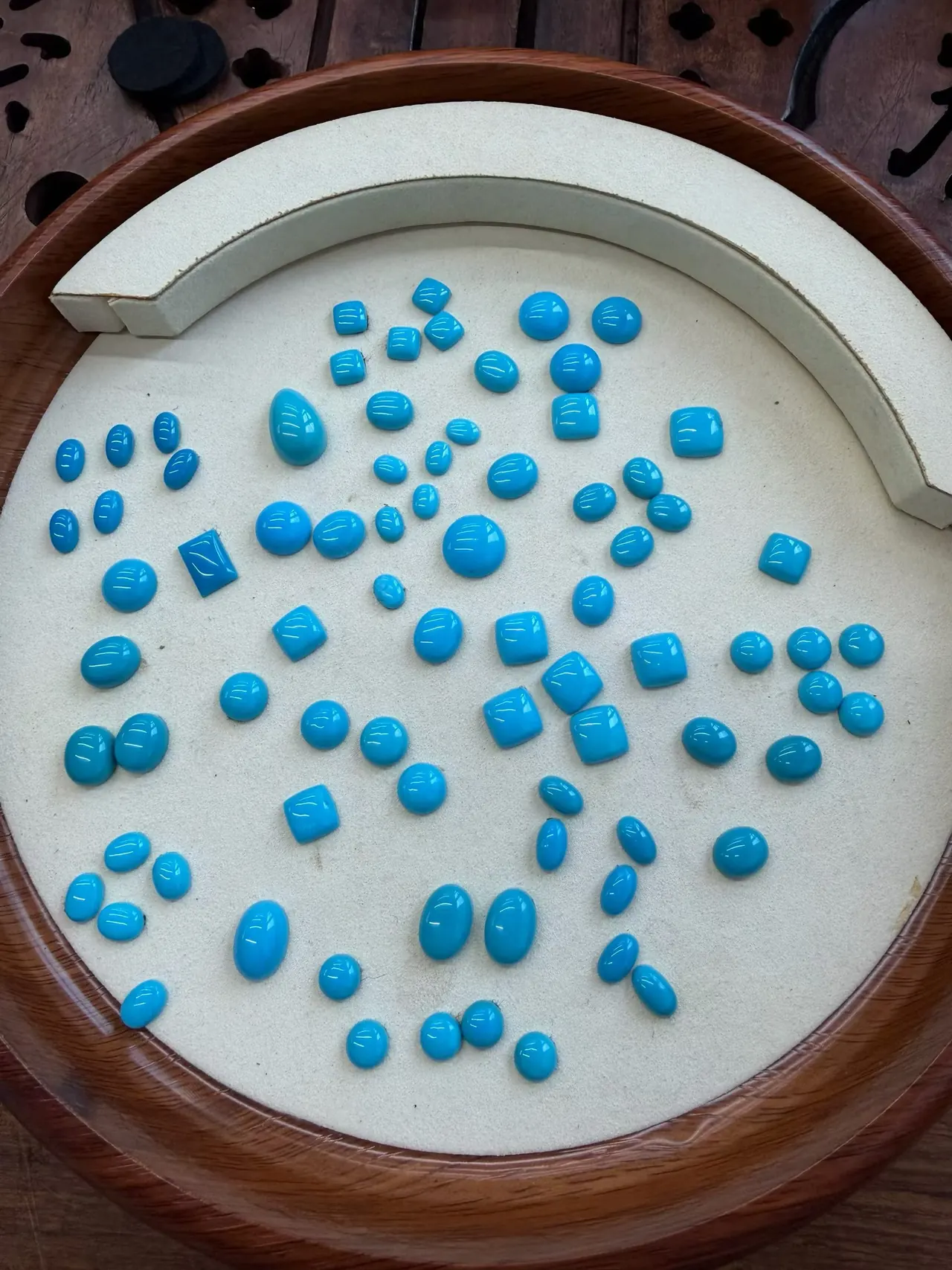 Blue cabochons of several shapes arranged on a padded tray.